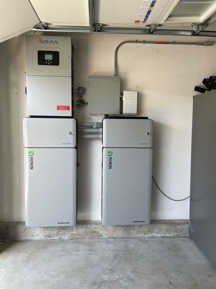 Sol-Ark inverter mounted above two Renon battery cabinets in a garage